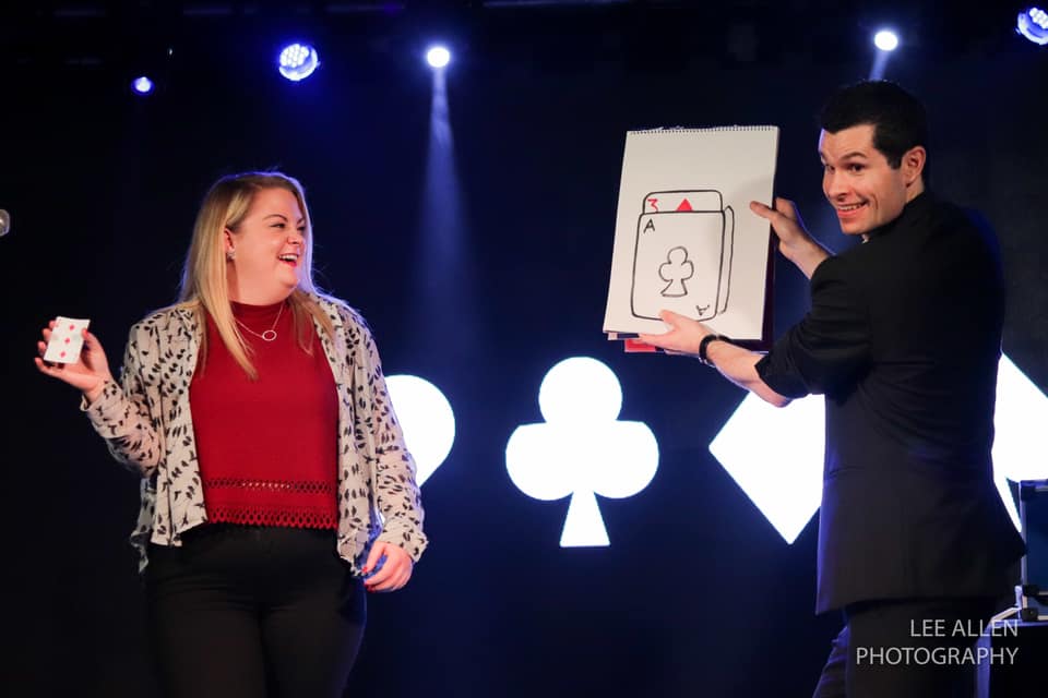 cabaret magician performing a magic show with a guest on stage